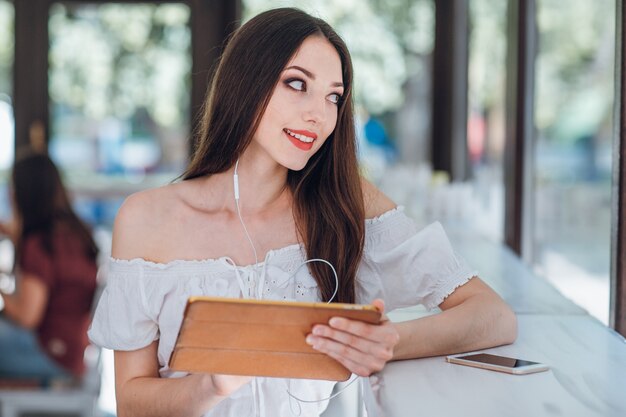 Young girl smiling with a tablet in hands while looking out a window