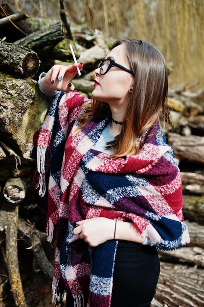 Free photo young girl smoking cigarette outdoors background wooden stumps concept of nicotine addiction by teenagers