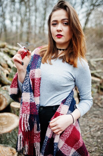 Young girl smoking cigarette outdoors background wooden stumps Concept of nicotine addiction by teenagers