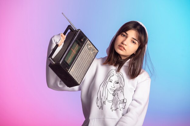 Young girl in sport outfits and short hairstyle holding a vintage radio. 