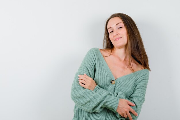 Young girl standing arms crossed in knitwear and looking charming , front view.