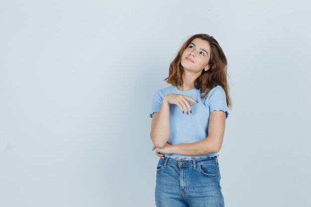Young girl standing in dreaming pose in t-shirt, jeans and looking cute , front view.