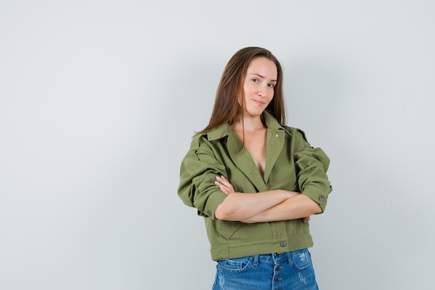 Free photo young girl standing with crossed arms in jacket, shorts and looking confident. front view.