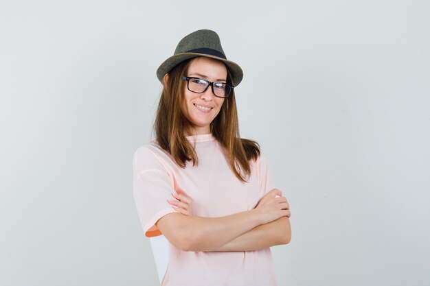 Young girl standing with crossed arms in pink t-shirt hat and looking confident 