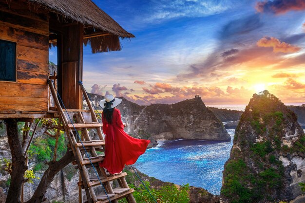 Free photo young girl on steps of house on tree at sunrise in nusa penida island, bali in indonesia