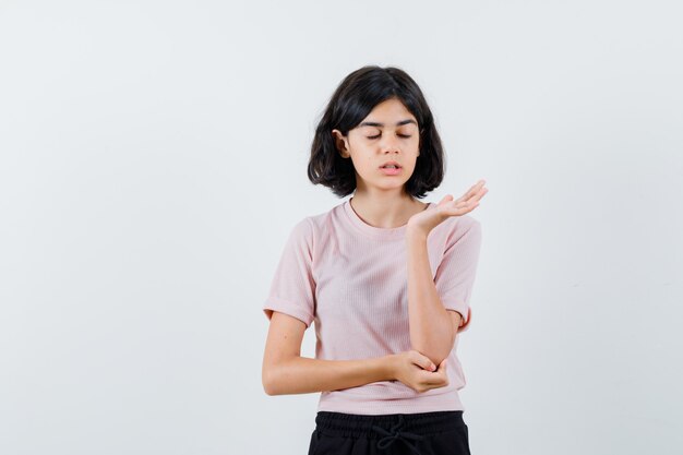 Young girl stretching hands as holding something imaginary while closing eyes in pink t-shirt and black pants and looking happy