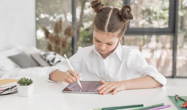 Young girl studying on tablet with pen