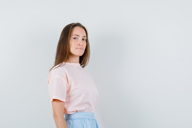 Young girl in t-shirt, skirt looking at camera and looking confident , front view.