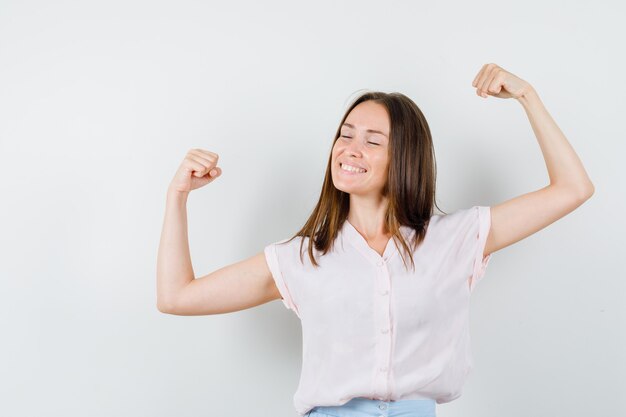 Young girl in t-shirt, skirt showing winner gesture and looking blissful , front view.