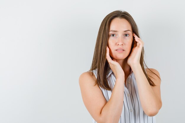 Young girl in t-shirt touching her face and looking graceful , front view.