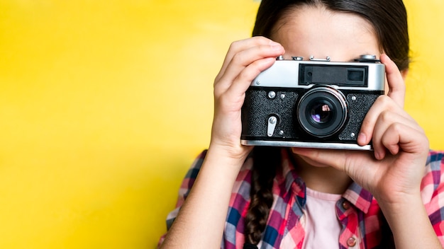 Foto gratuita ragazza che cattura una maschera con una retro macchina fotografica