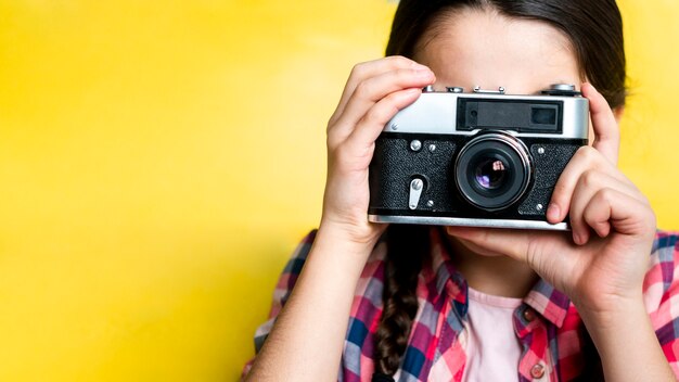 Молодая девушка фотографирует с ретро камерой