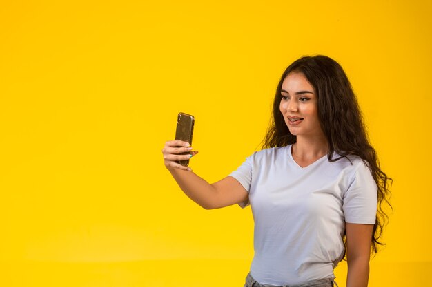 그녀의 스마트 폰으로 selfie를 복용하는 어린 소녀.