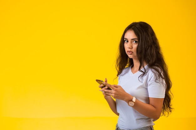 Young girl talking and chatting at her phone while looking aside.