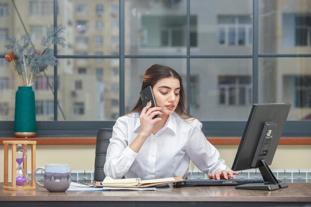 PCで作業しながら電話で話している若い女の子高品質の写真