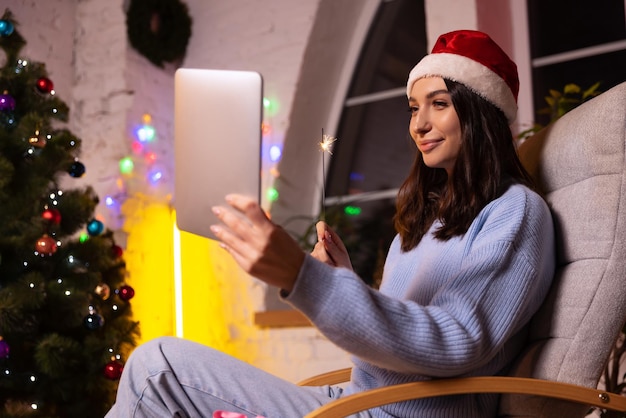 Young girl talking with friends by means of video communication and celebrates winter holidays