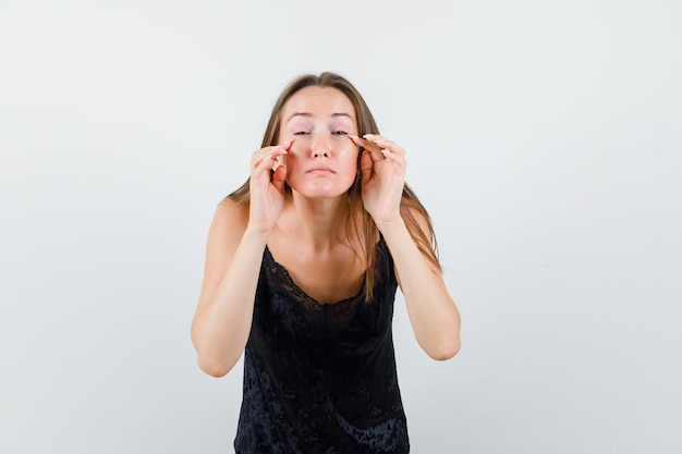 Young girl touching her eye bags in black singlet front view.