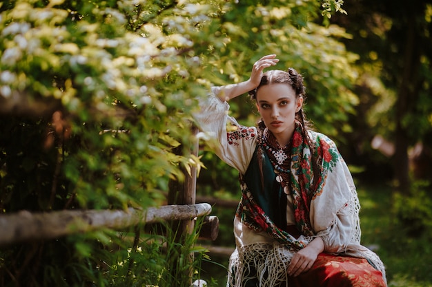 Young girl in a traditional Ukrainian dress is sitting on a bench in the park