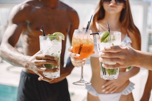 Young girl and two her multiracial male friends relaxing on a sunbeds near swimming pool