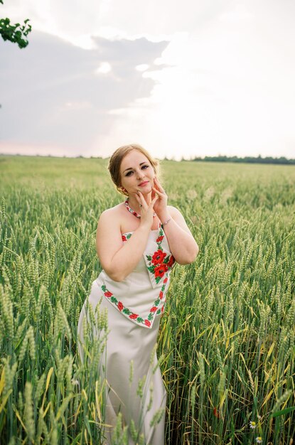 Молодая девушка в украинском национальном костюме позирует на поле венков