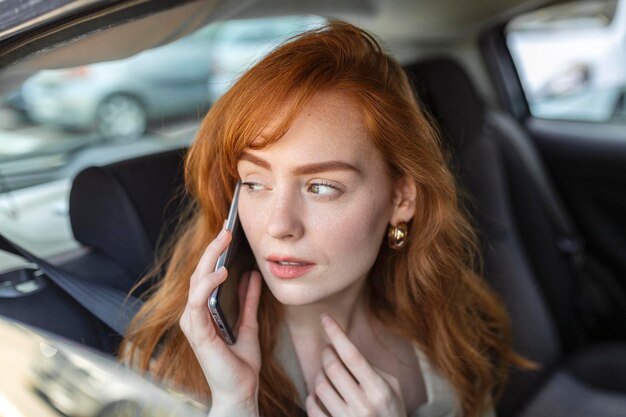 Young girl uses a mobile phone in the car Technology cell phone isolation Internet and social media Woman with smartphone in her car Girl is using a smartphone in car