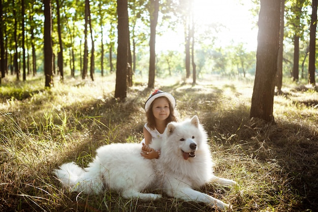 Young girl walking, playing with dog in park at sunset.