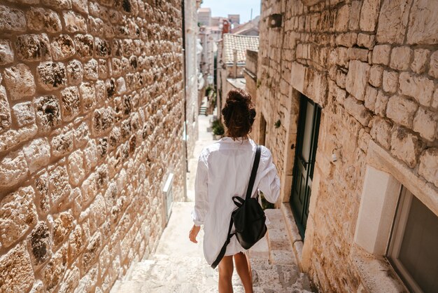 Молодая девушка прогуливается по древним узким улочкам в прекрасный летний день