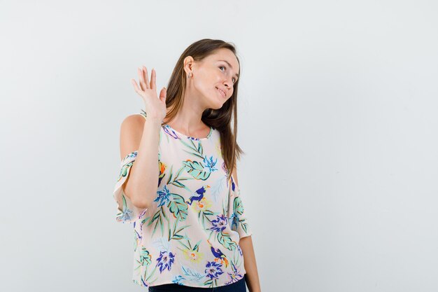 Young girl waving hand to say goodbye in shirt, jeans and looking glad , front view.
