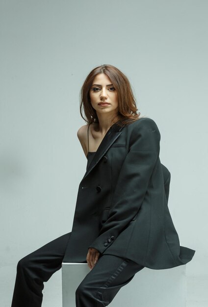 Young girl wearing black suit and looking at the camera on white background High quality photo