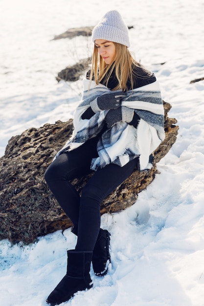 雪の上に座って毛布を着ている若い女の子