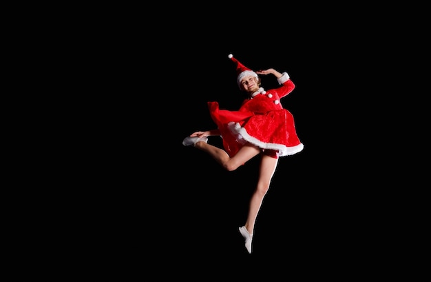 Una giovane ragazza che indossa un costume da babbo natale sta volando. natale, infanzia, fiaba.