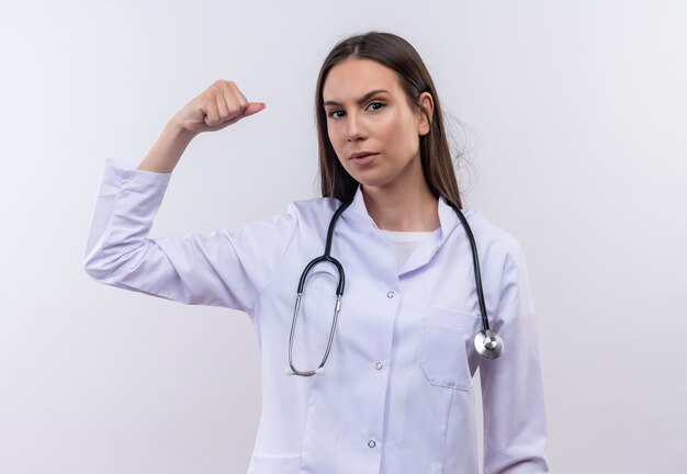 young girl wearing stethoscope medical gown doing strong gesture on isolated white wall