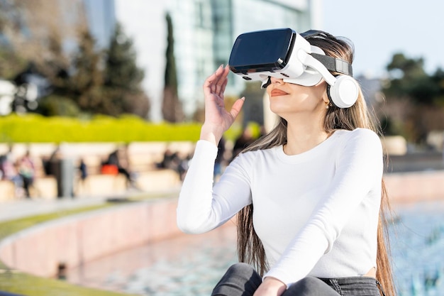 Молодая девушка в VR-наборе сидит в парке Фото высокого качества
