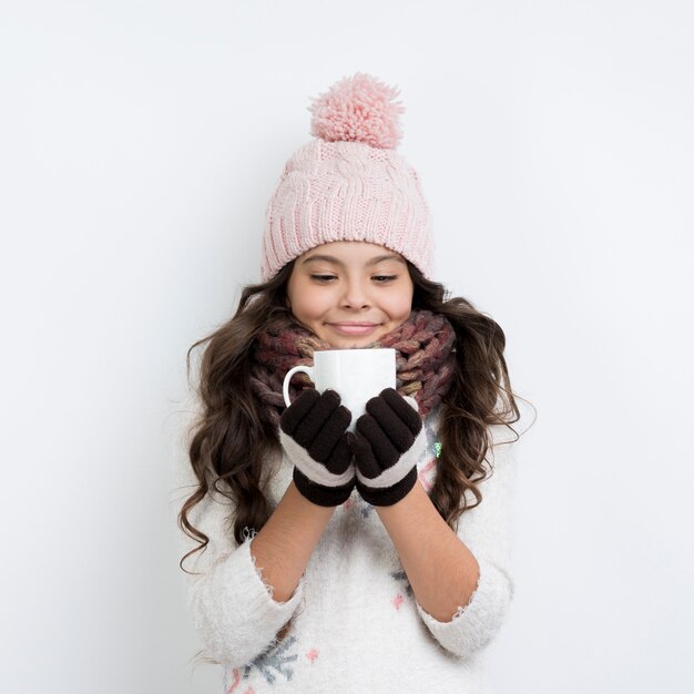 Young girl wearing winter clothes and drinking tea