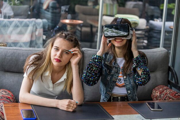 Free photo young girl wearingvr glasses and her friend is bored