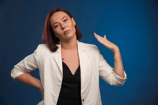 Young girl in white blazer blowing herself. 