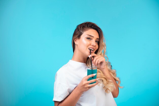 Young girl in white shirt drinking blue cocktail