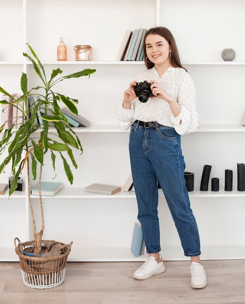 Young girl in white shirt standing with an old camera