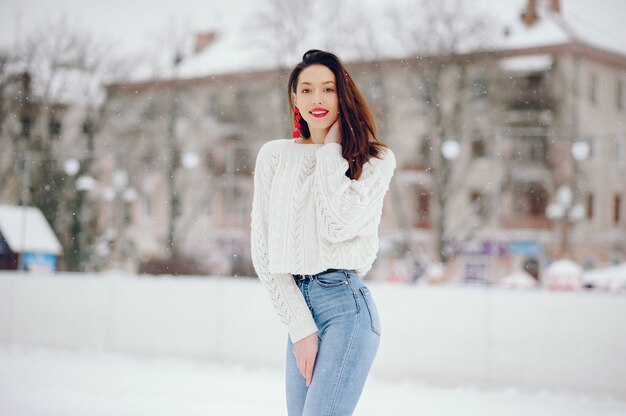 Young girl in a white sweater standing in a winter park