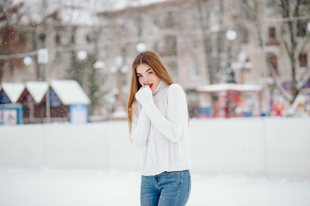 Young girl in a white sweater standing in a winter park