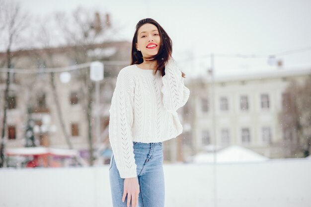 冬の公園に立っている白いセーターの少女