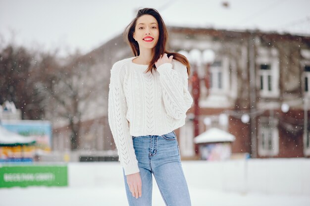 Young girl in a white sweater standing in a winter park