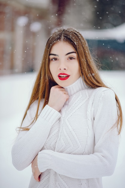 Foto gratuita ragazza in un maglione bianco che sta in un parco di inverno