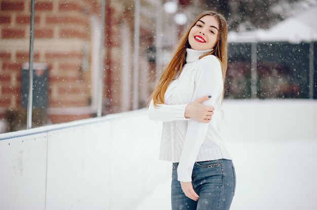 Young girl in a white sweater standing in a winter park