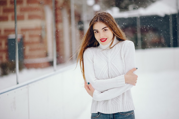 冬の公園に立っている白いセーターの少女