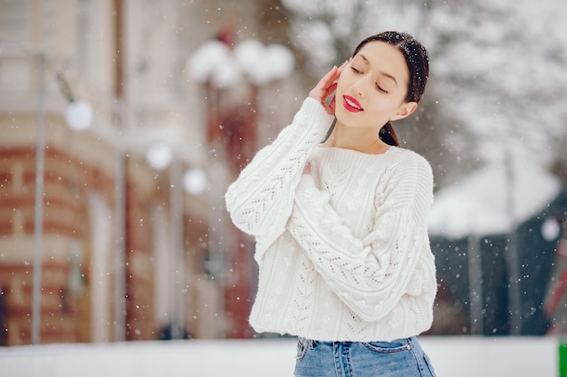 Young girl in a white sweater standing in a winter park