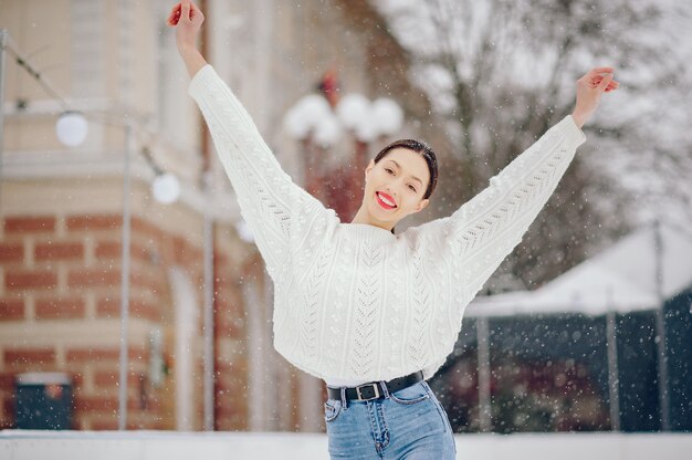 Young girl in a white sweater standing in a winter park