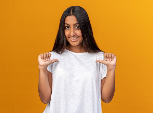 Young girl in white t-shirt looking at camera smiling confident pointing at herself 