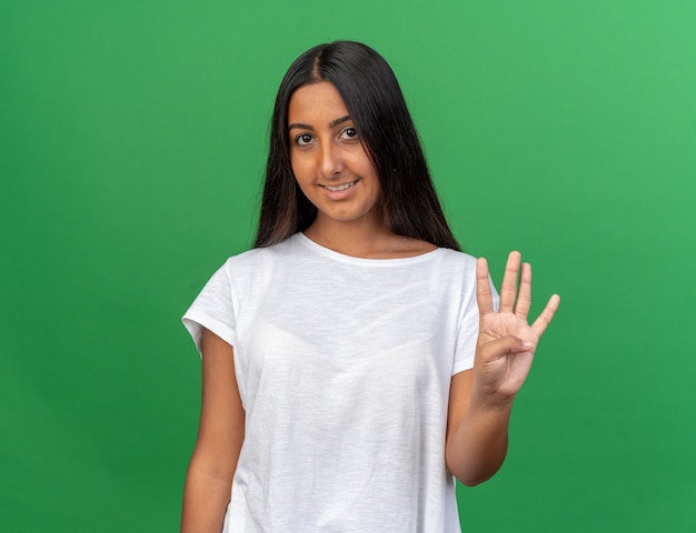 카메라를보고 웃 고 손가락 번호 4로 가리키는 흰색 티셔츠에 어린 소녀