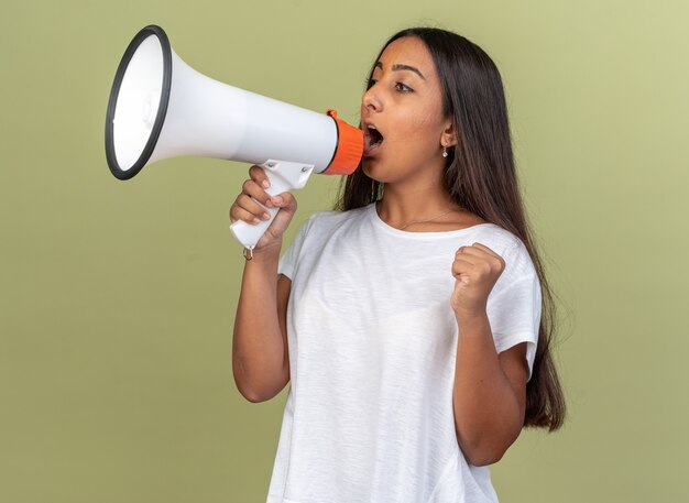 Young girl in white t-shirt shouting to megaphone clenching fist 